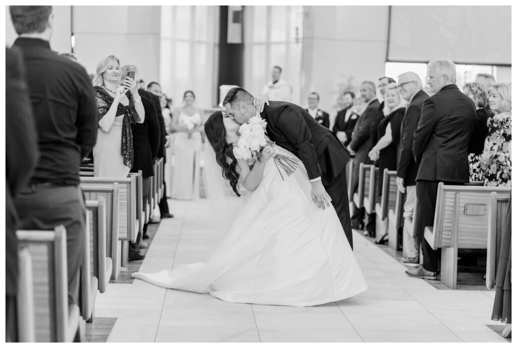 Hanah and Mike after their ceremony, doing a dip kiss in the middle of the aisle 