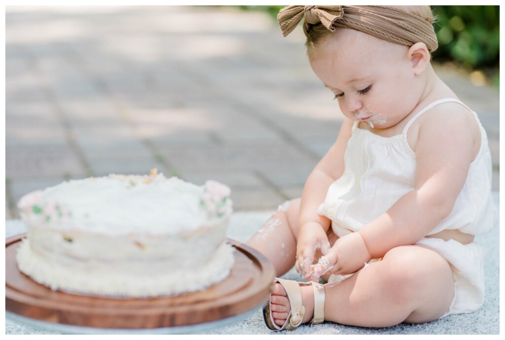 One-year-old enjoying a cake smash at a milestone photography session in Columbus